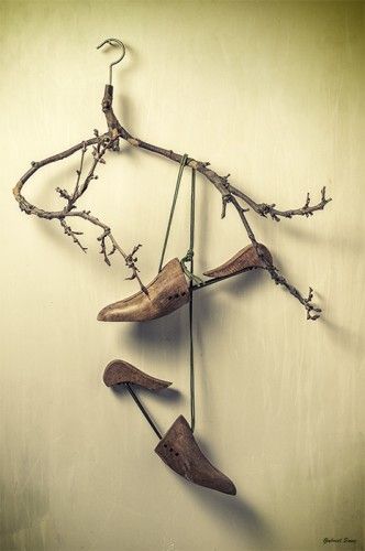 ramas de arbol con formando una percha   de la que cuelgan dos ormas de madera