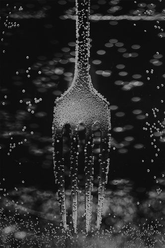 Foto de tenedor sumergido en agua formandose burbujas sobre el y su entorno